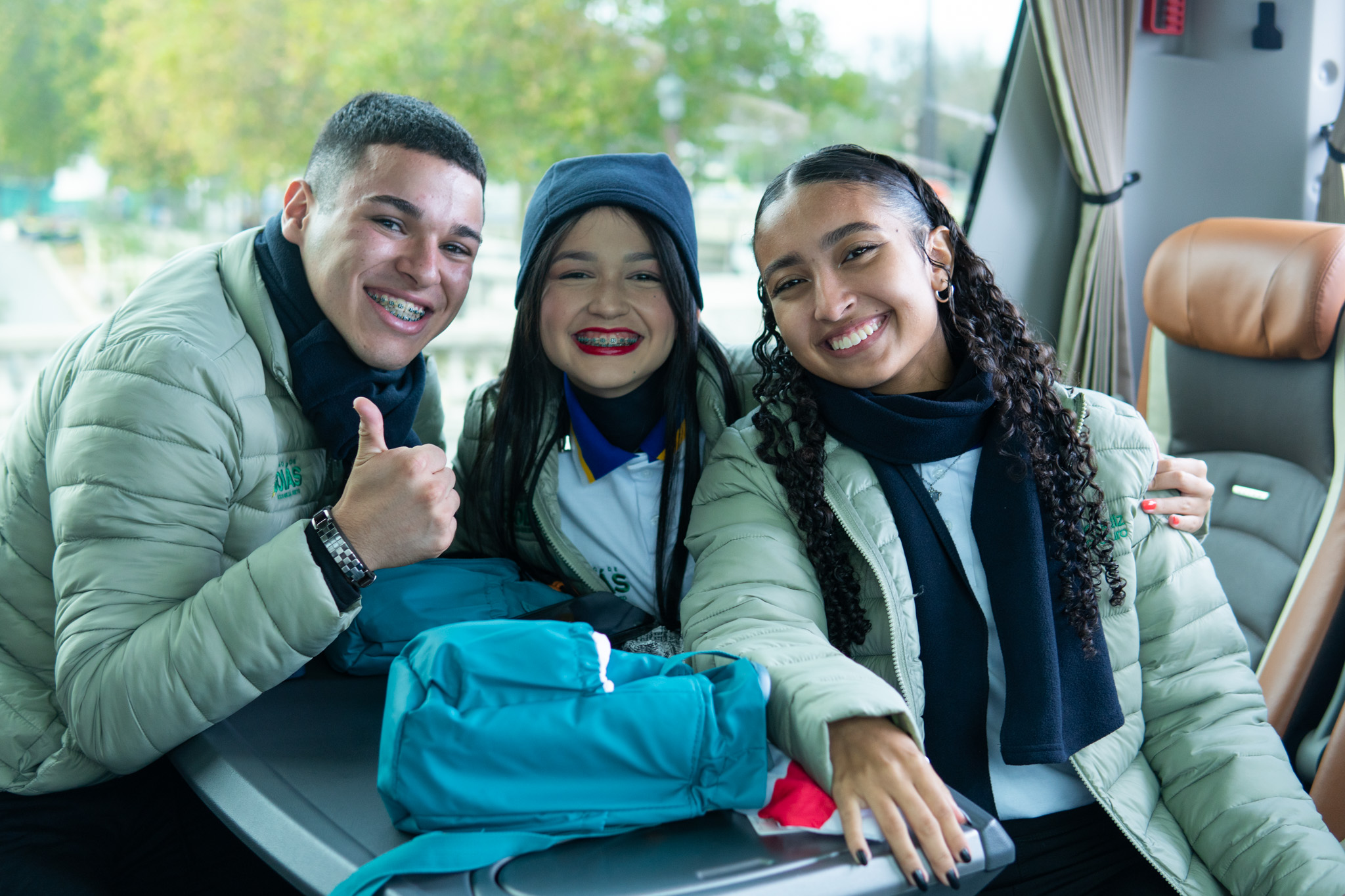 Três estudantes do Programa Aprendiz do Futuro sorrindo no ônibus durante sua jornada de intercâmbio na França e Suíça.