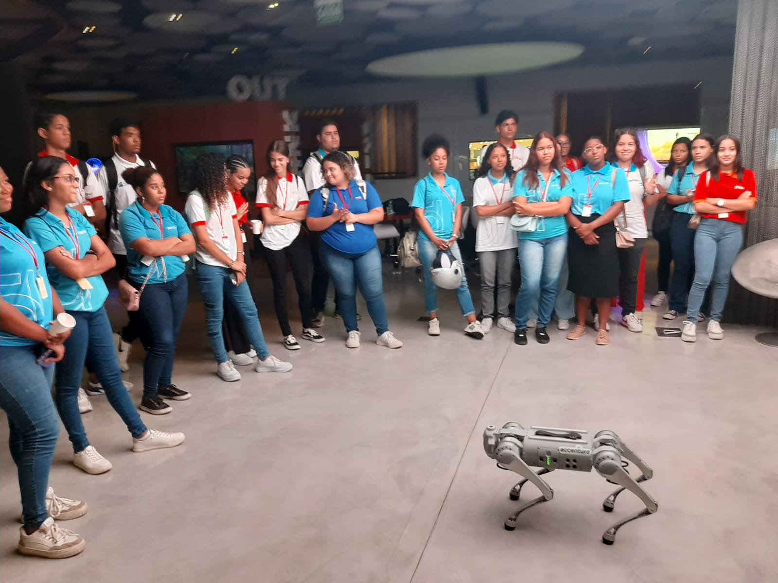 Jovens aprendizes do polo Recife observam atentos um robô em ação durante visita ao Innovation Center da Accenture Brasil. A atividade é parte de uma experiência de imersão em tecnologia e inovação, promovendo o contato dos jovens com ferramentas de ponta.